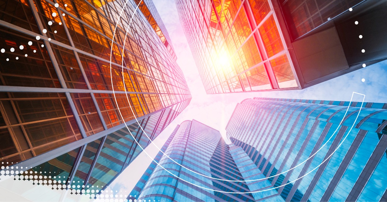 Blick aus der Froschperspektive auf moderne Hochhäuser aus Glas mit reflektierender Fassade und Sonneneinstrahlung