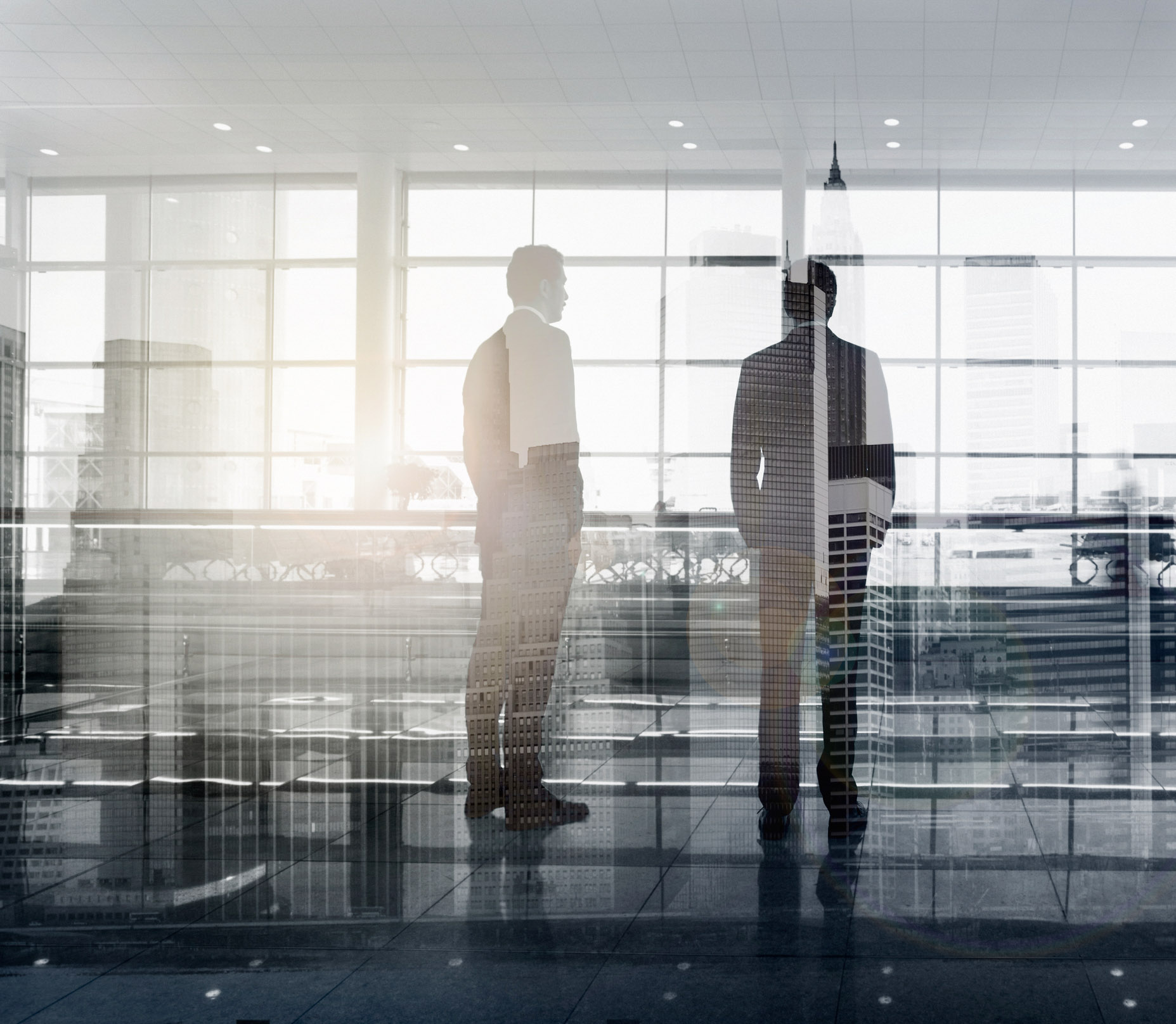 Silhouettes of two business professionals in modern office.