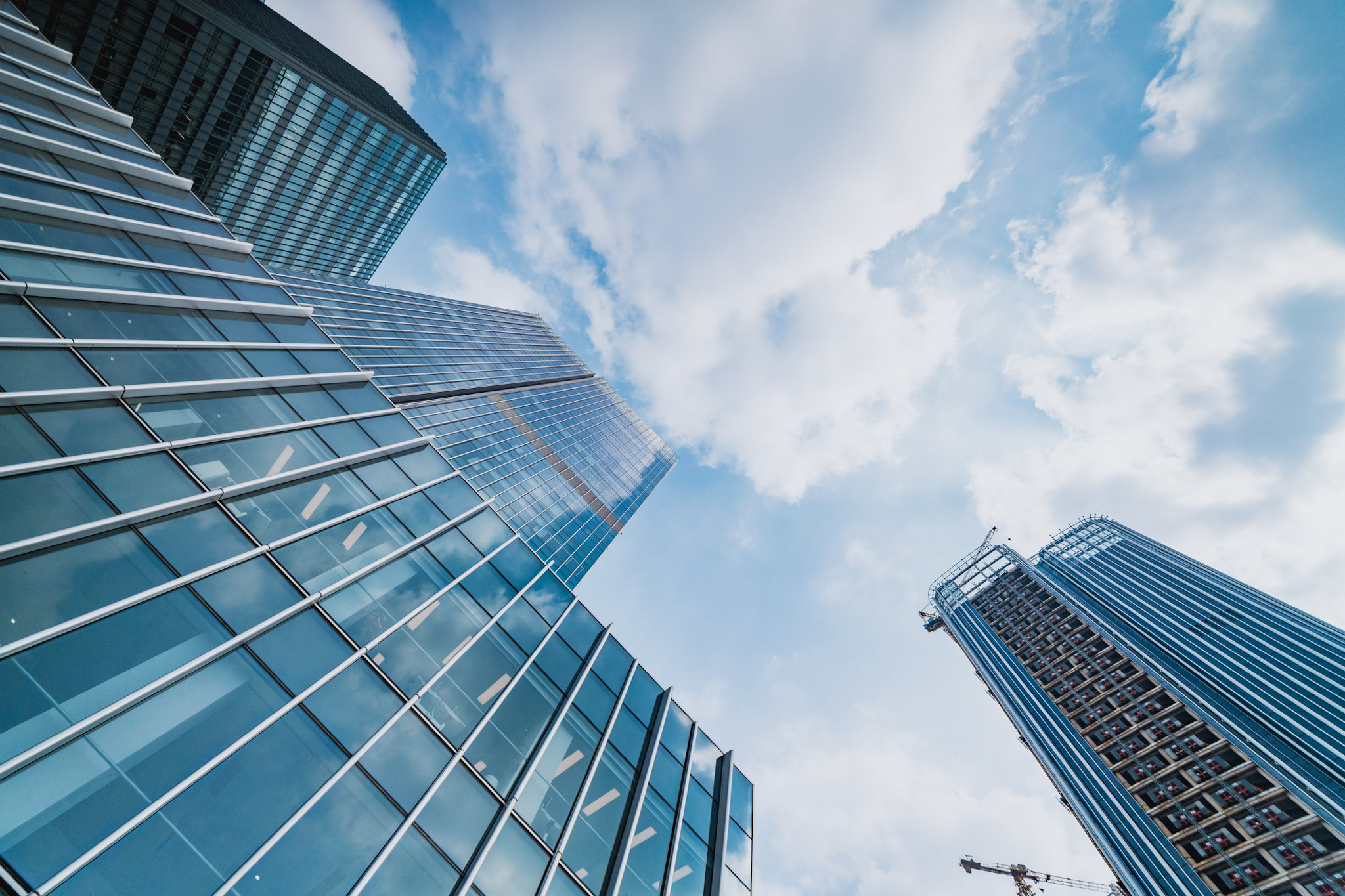Upward view of modern glass skyscrapers against a bright sky, symbolizing growth and connected IT environments.