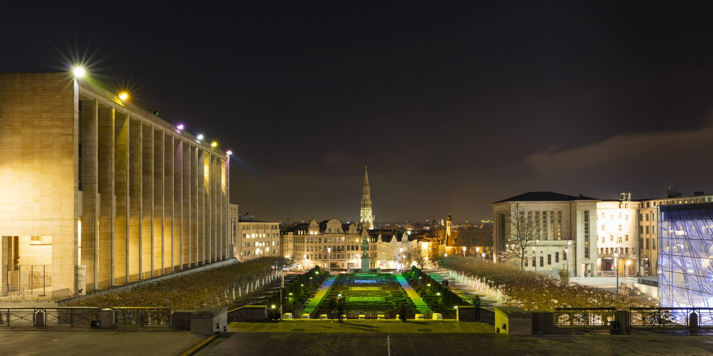 Night panorama of Brussels cityscape with illuminated Mont des Arts gardens and historic church spire, representing European digital policy hub