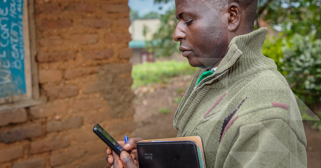 Community health worker checks on a patient's welfare using the Medic Mobile app on his cellphone