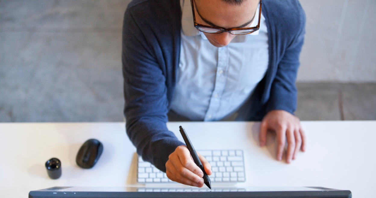 Man using a stylus pen on desktop screen.