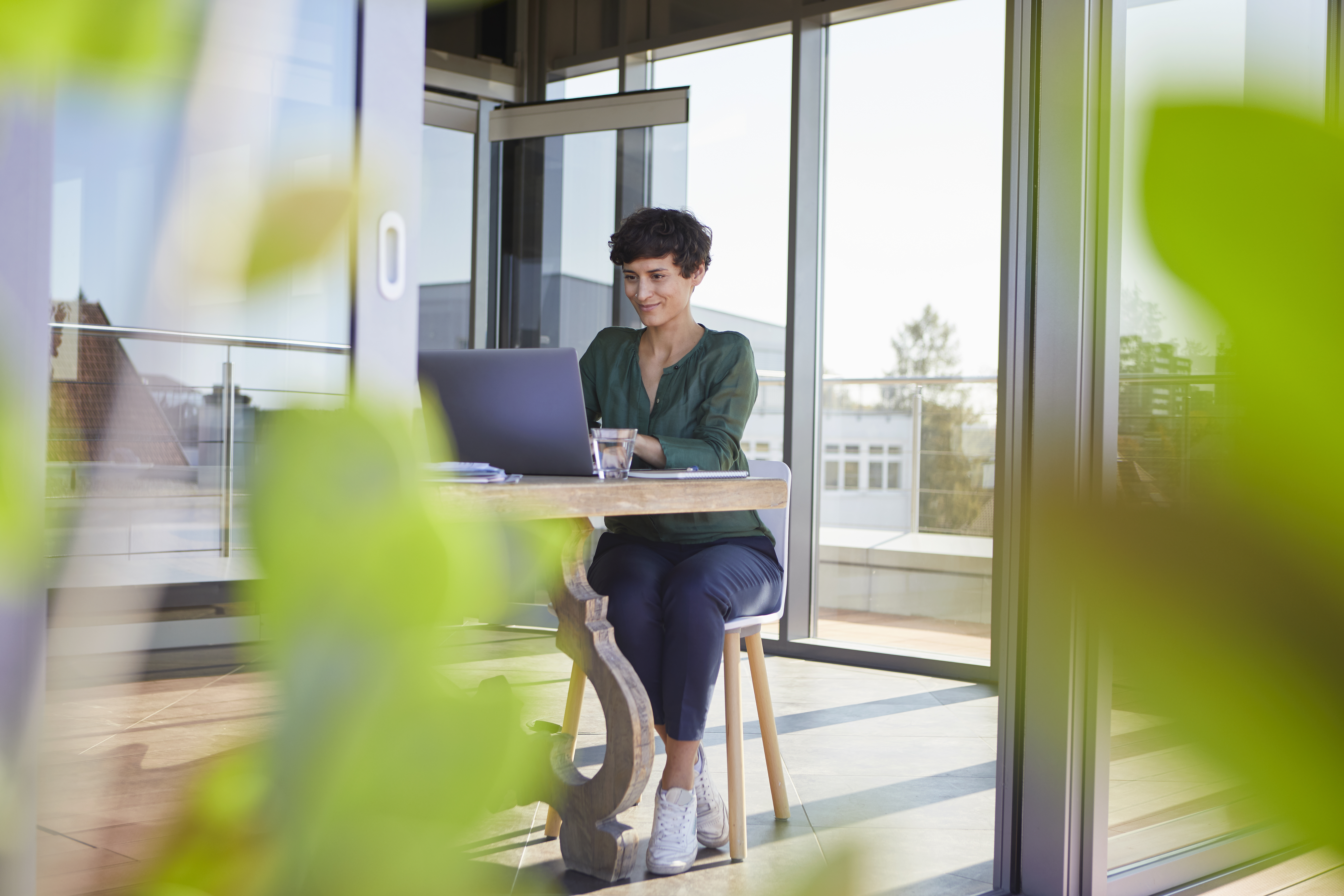 Woman sitting at a table working on laptop.