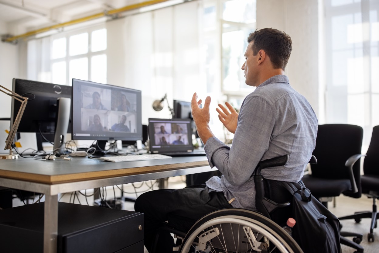 Man in wheelchair at desk on a video call.
