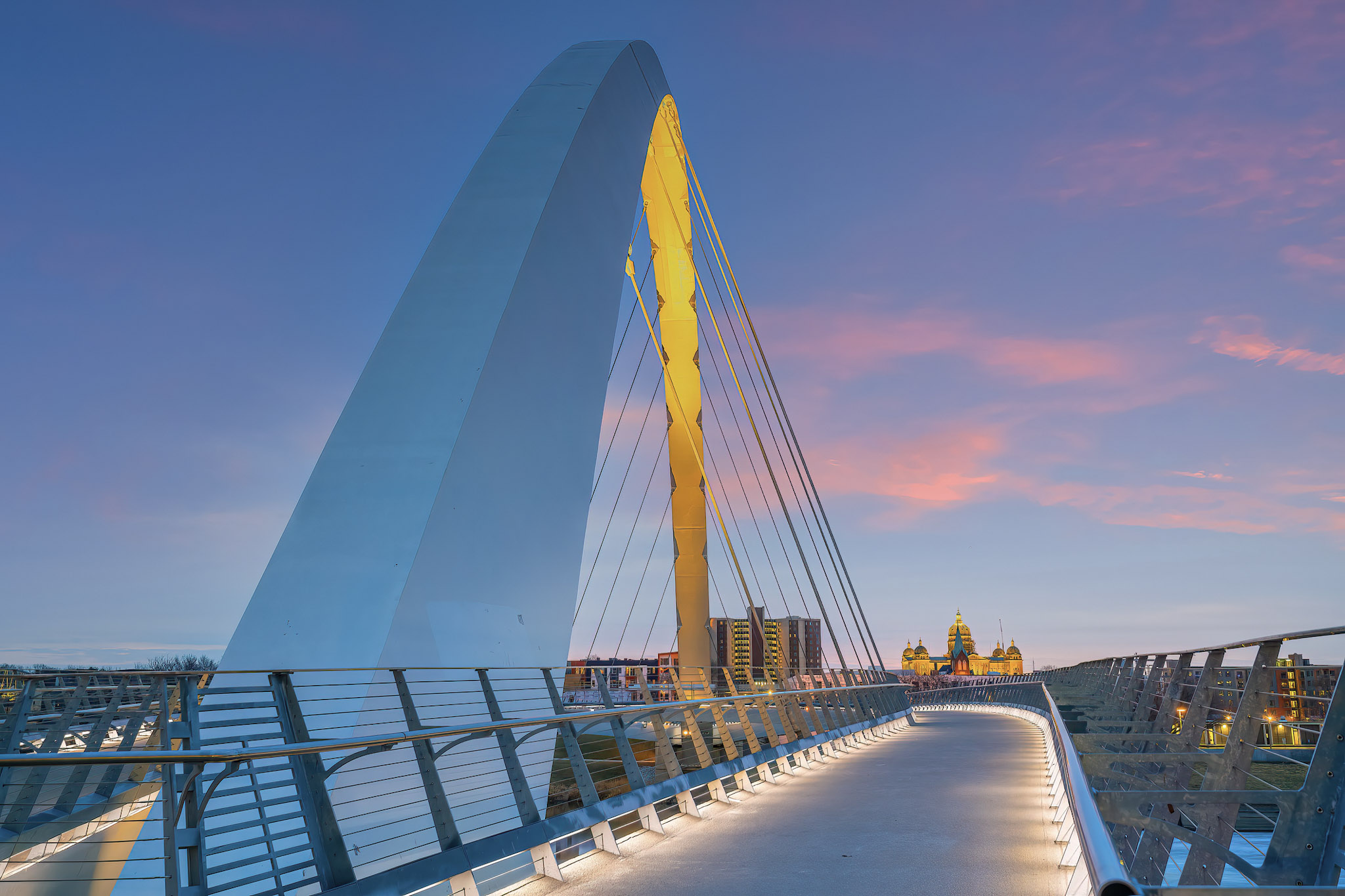 Modern illuminated pedestrian bridge at sunset.