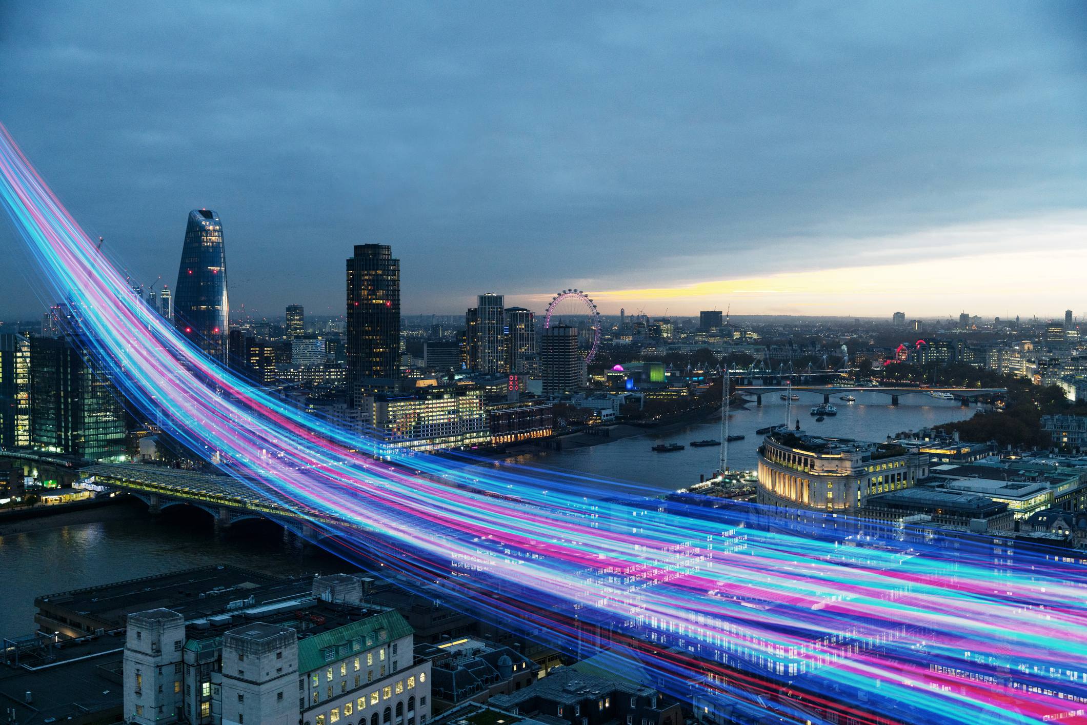 Aerial view of London skyline at dusk with glowing blue and pink digital data streams sweeping across the Thames, representing cloud automation velocity